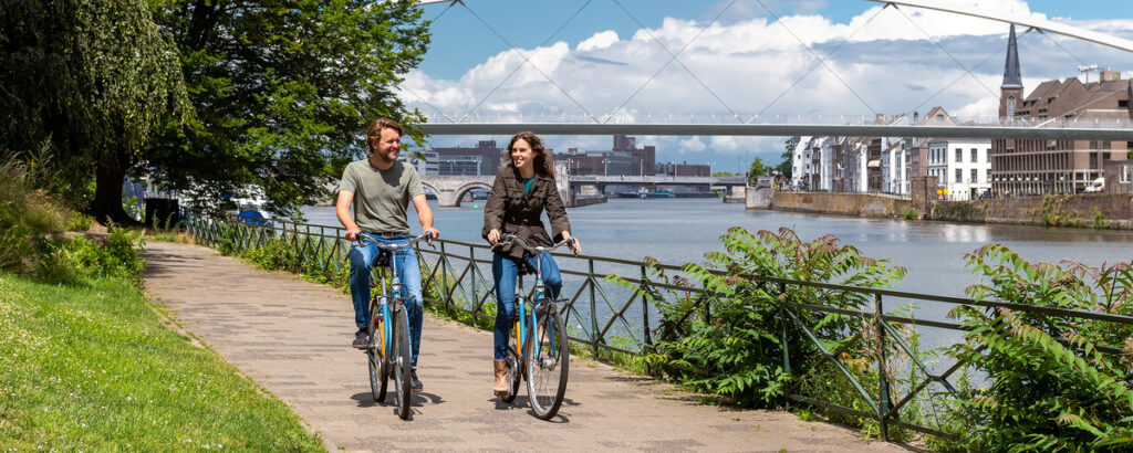 twee mensen fietsen langs water en groen in stedelijke omgeving