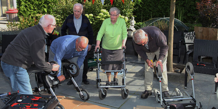 groep ouderen met rollators bij een tafel in een buitenruimte
