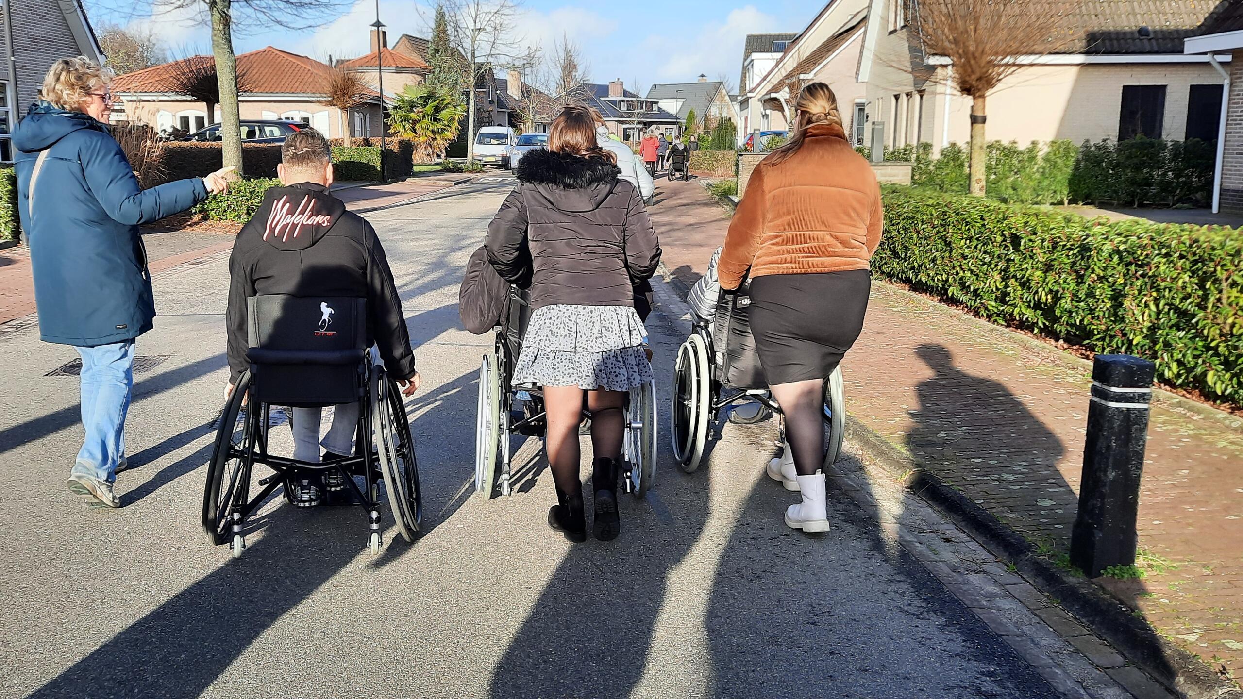 rolstoelgebruikers wandelen samen in een rustige straat met bomen en gebouwen
