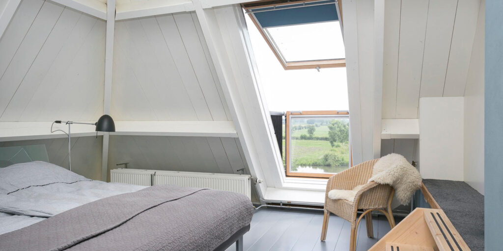 comfortabele slaapkamer met dakraam en uitzicht op buiten
