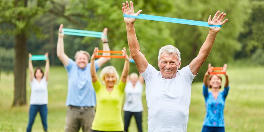 Ouderen trainen met weerstandsbanden in een park