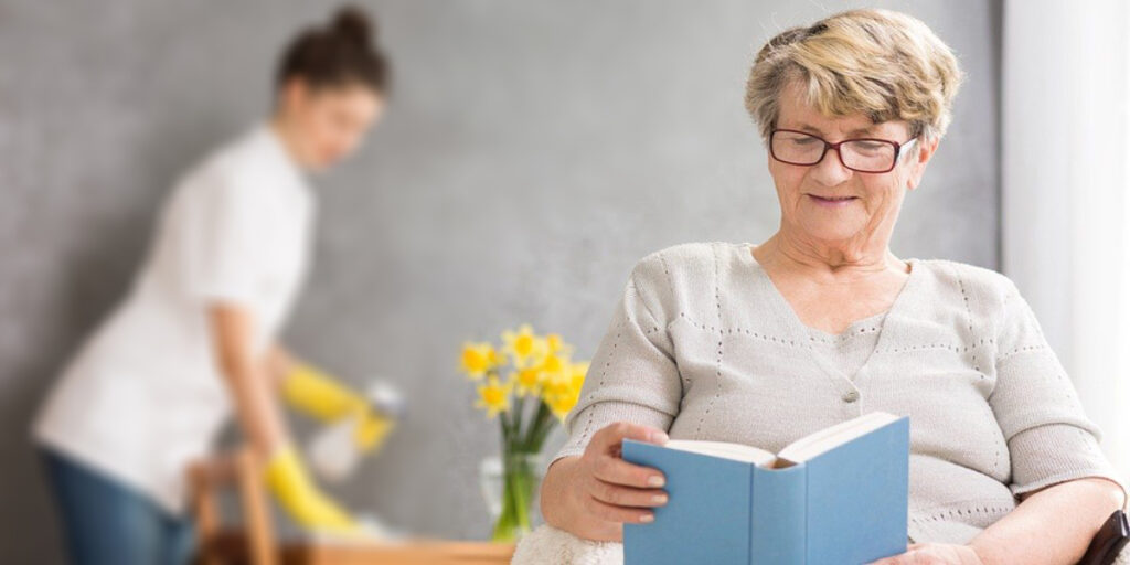 Oudere vrouw leest rustig een boek in een zorgomgeving